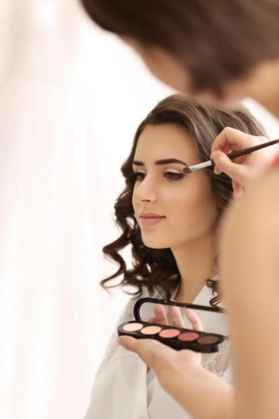 maquilleuse effectuant un maquillage des yeux sur une mariée