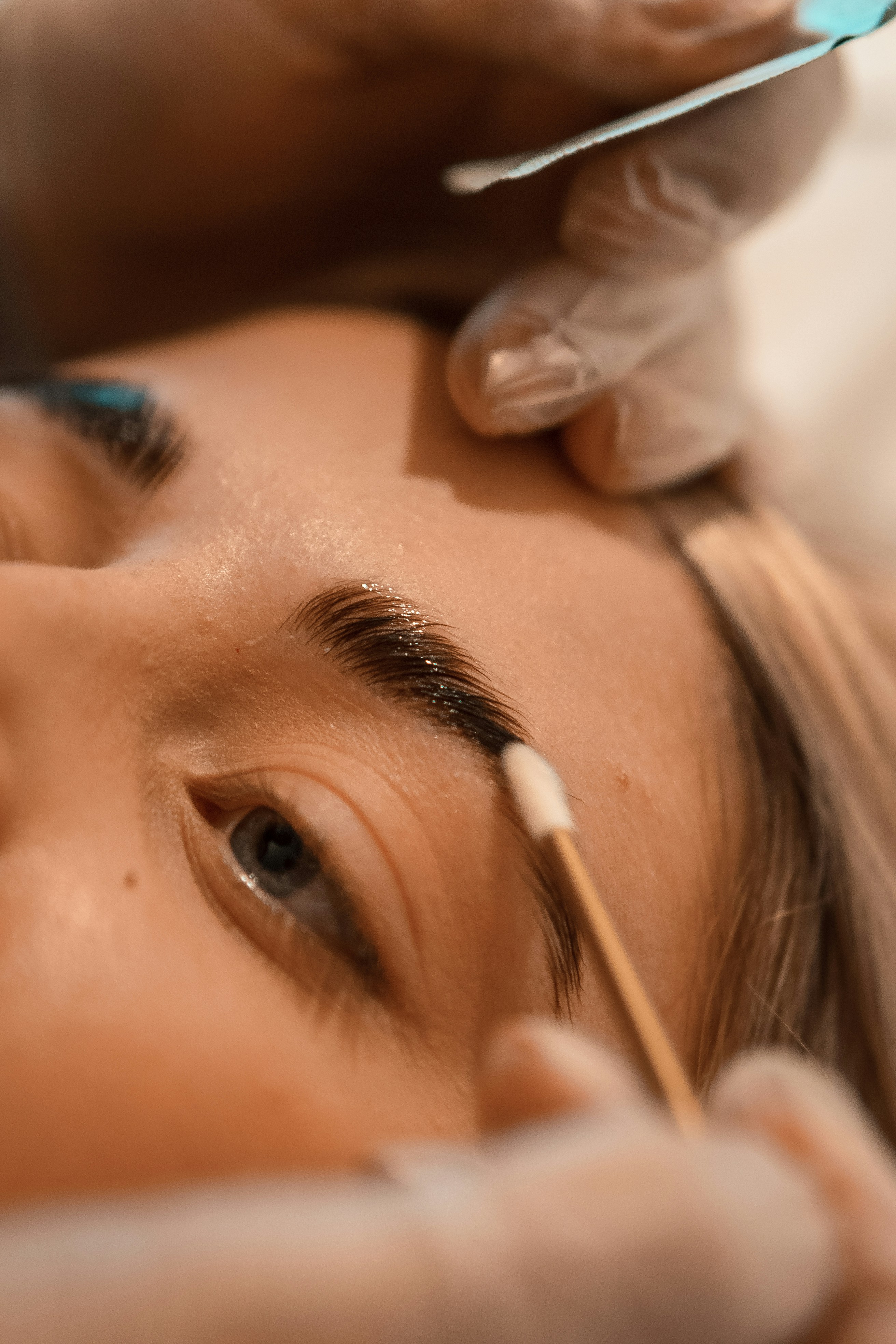 Femme qui prodigue un brow-lift et une teinture sur les sourcils d'une autre femme.