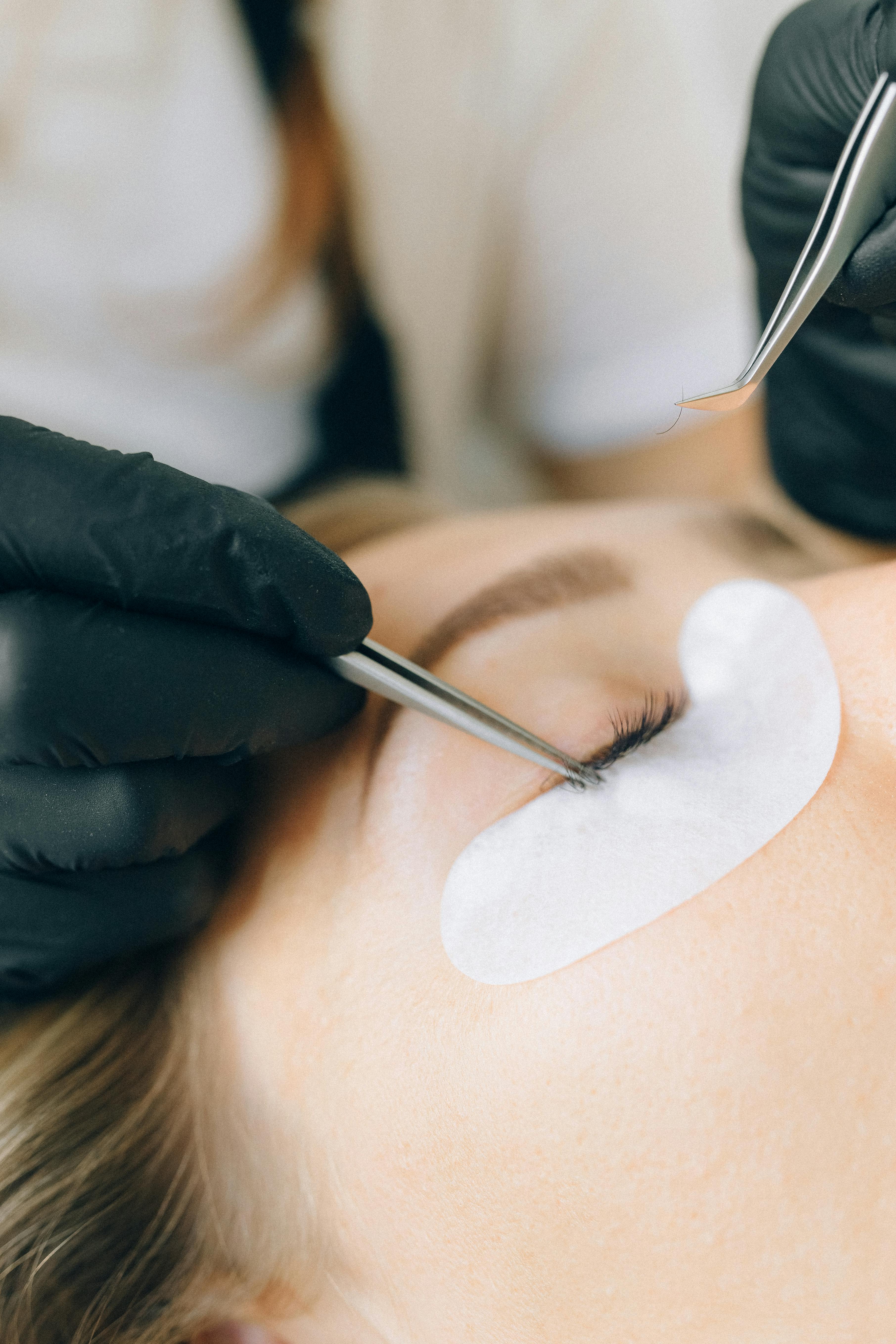 Femme qui réalise une extension de cils à une autre femme.